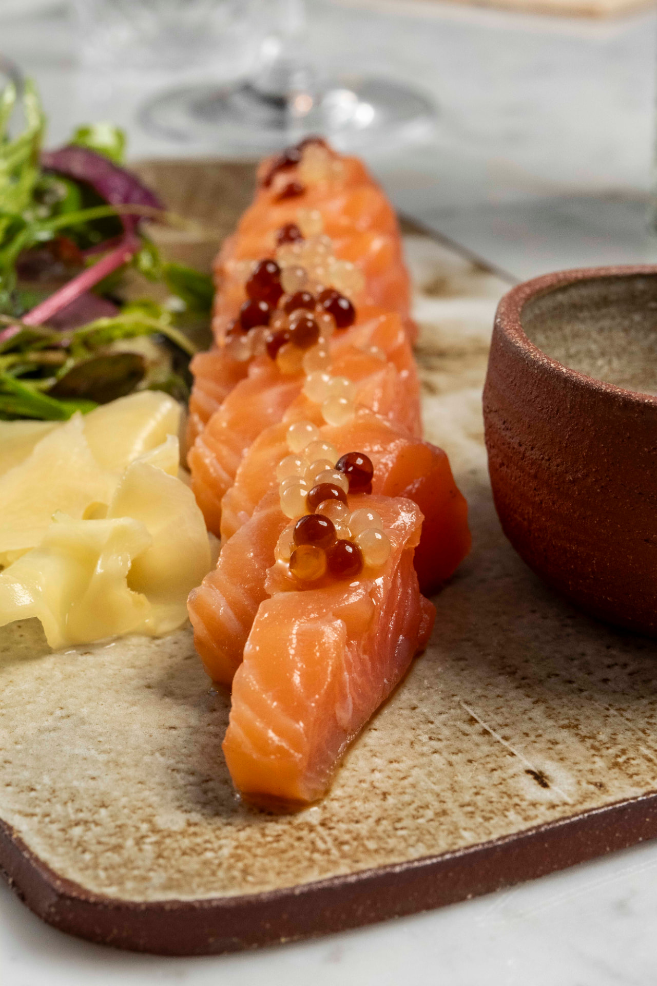 Sashimi di salmone con perle di agrumi su ceramica